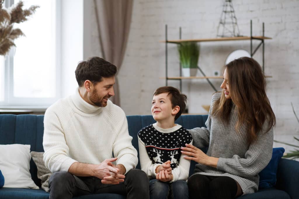 How to get your child to stop talking back - kid talking with mom and dad, sitting on the sofa