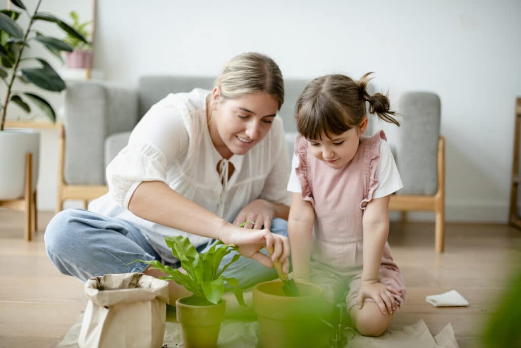 parent influence on children - mother and daughter planting flowers in brown pots