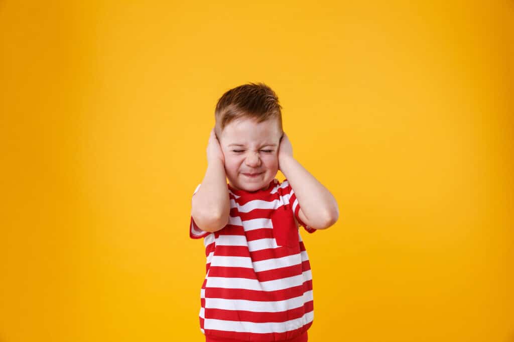 parent yelling at child - young child with closed eyes and hands covering their ears