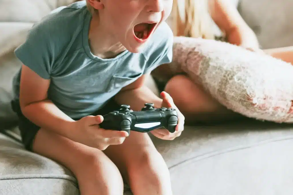 Boy yelling while holding a controller and playing a video game
