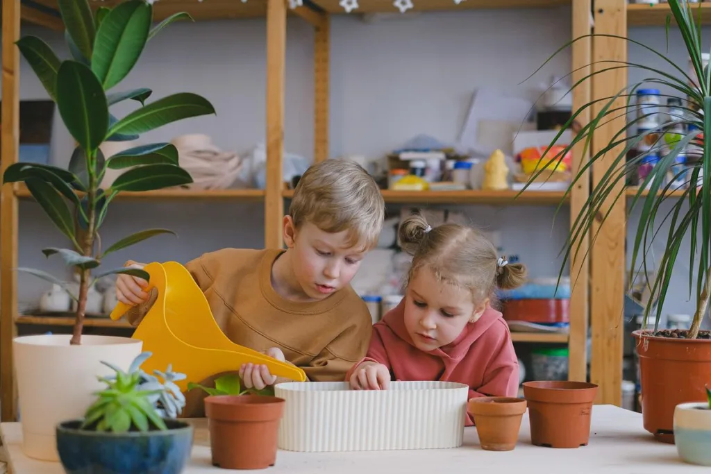 A boy and a girl carefully watering a plant
