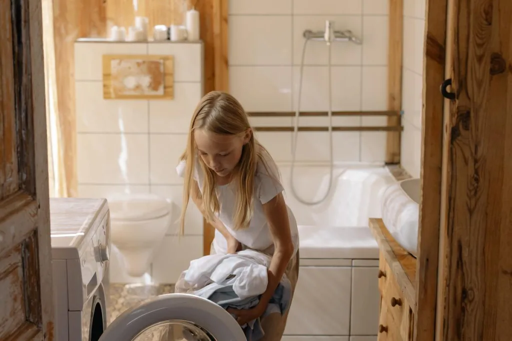 A teen girl putting laundry in the washing machine



