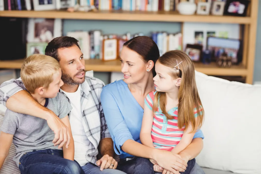 Parents and two kids sitting on the sofa, engaged in cheerful conversation