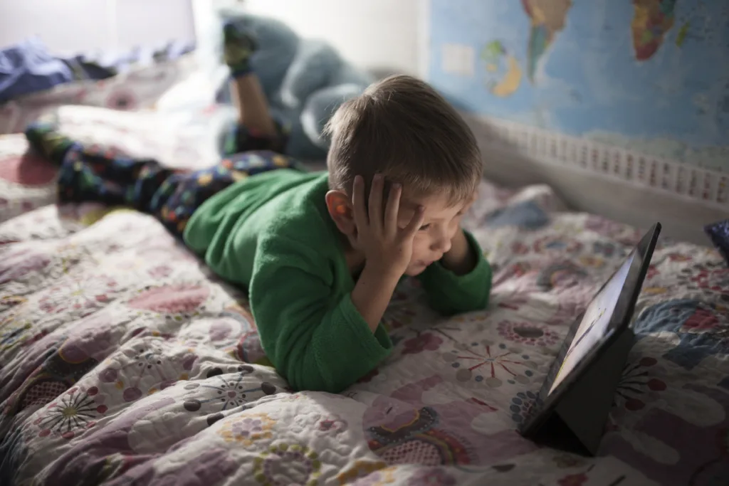 Negative effects of video games - Boy watching a movie on his tablet on the bed