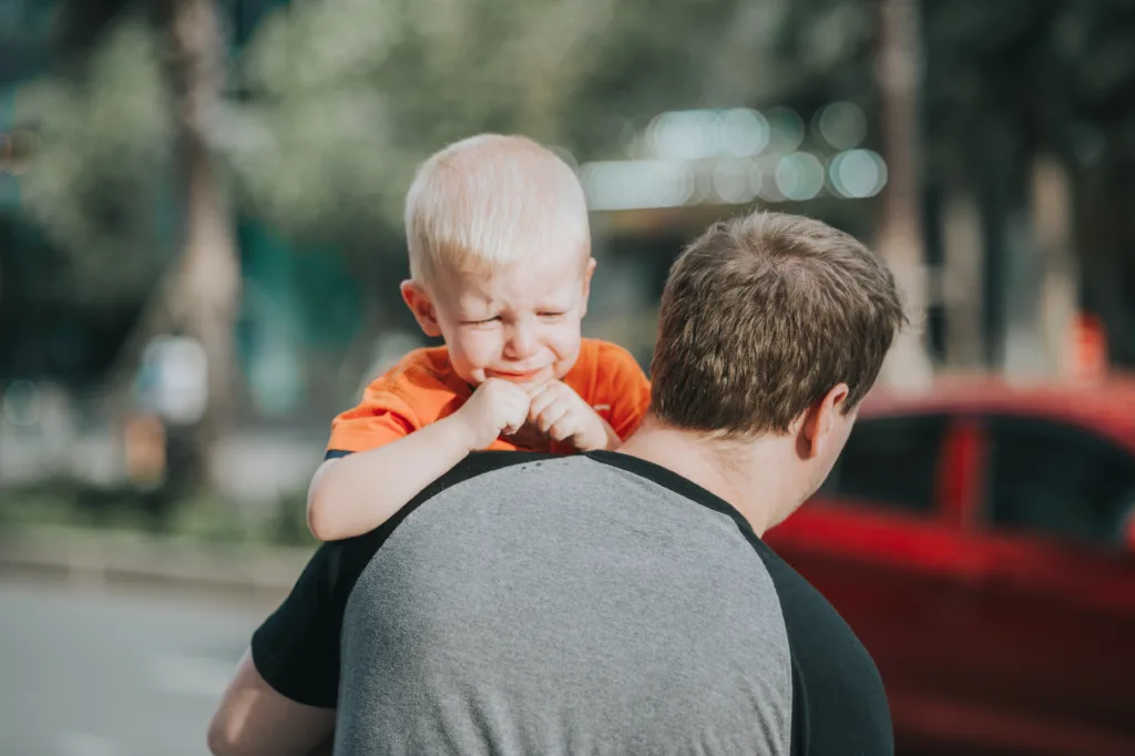 A caring dad comforting his crying toddler in his loving arms