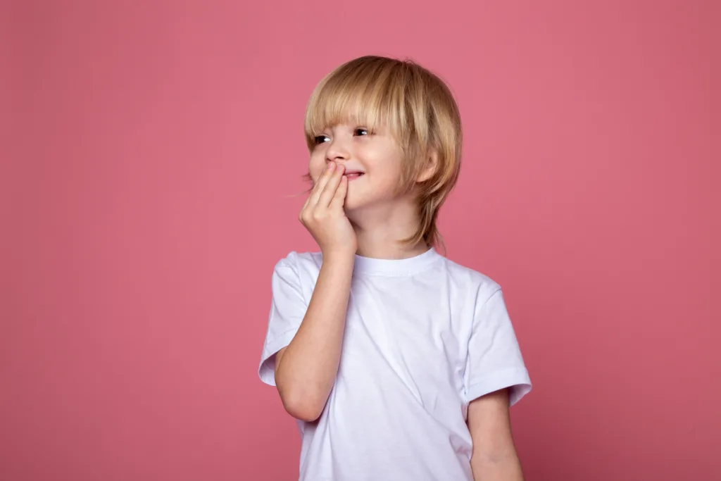 School-aged child covering mouth while giggling