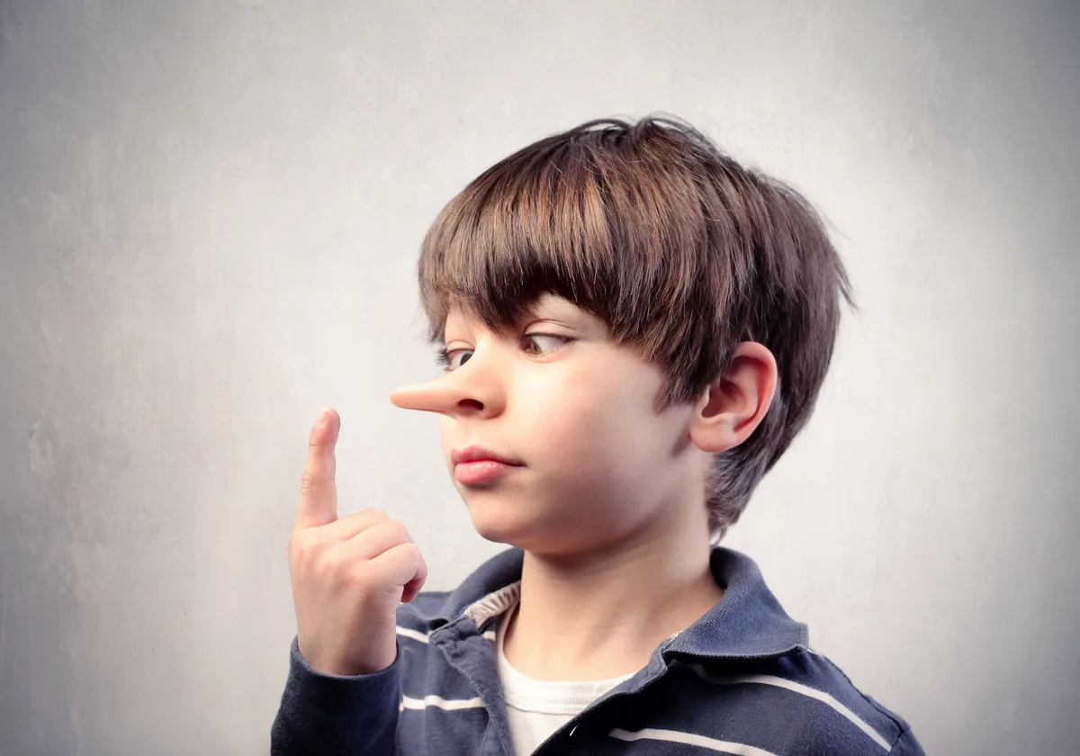 A boy looking cross-eyed at his index finger while measuring his growing nose