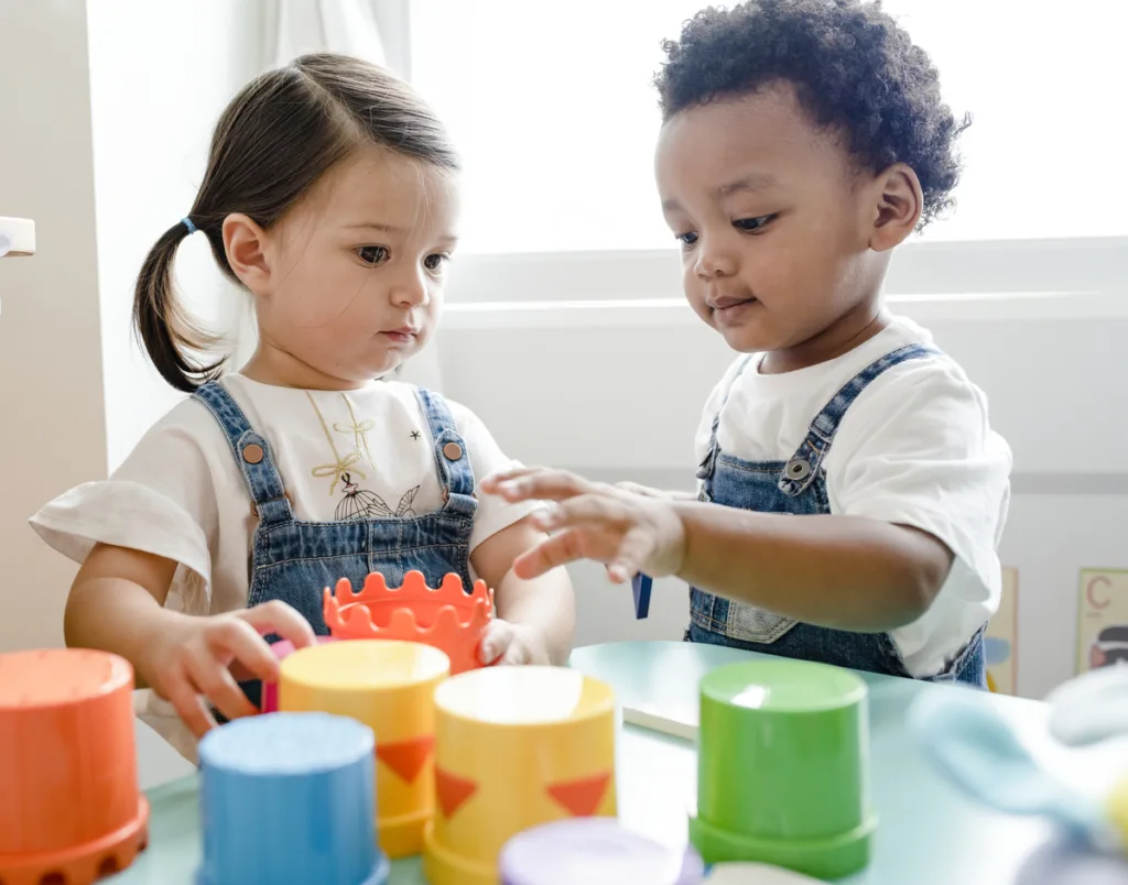 Two toddlers playing with stacking cups at daycare