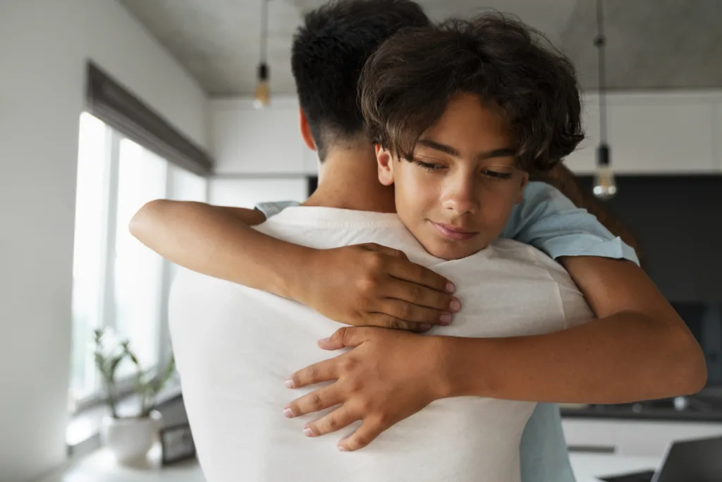 Supportive father hugging his adolescent son