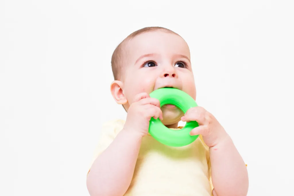 A toddler biting on a teething toy