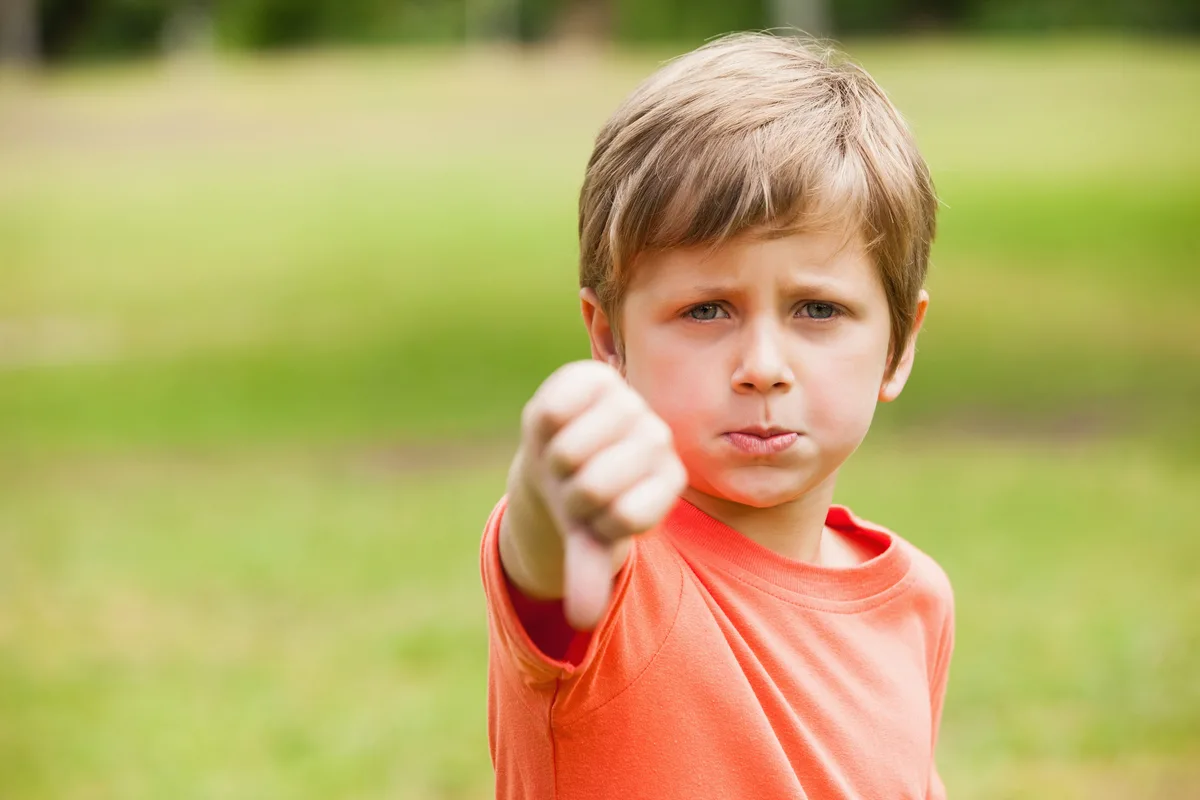 Boy in the park signaling thumbs down