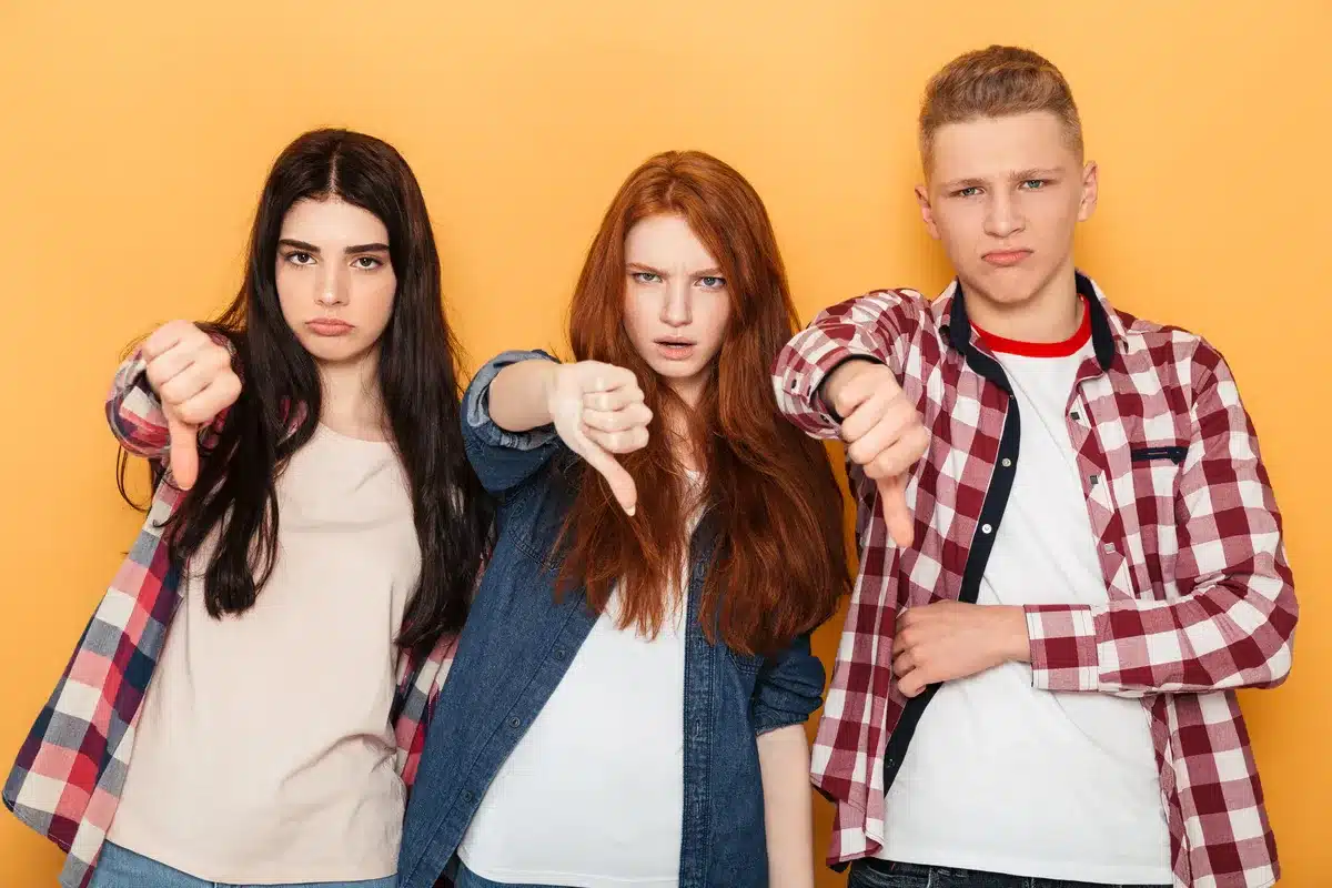 A group of teenagers showing their dissaproval with thumbs down