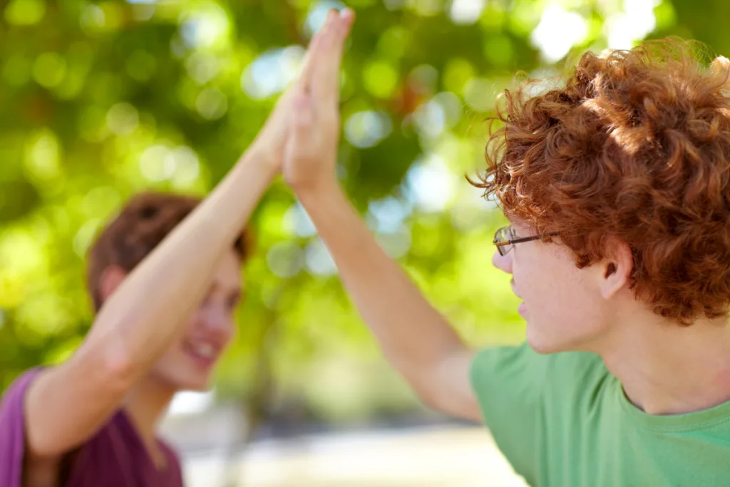 Two smiling teen boys sharing a high five