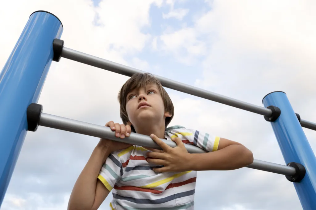 Sad-looking boy on monkey bars  looking in the distance