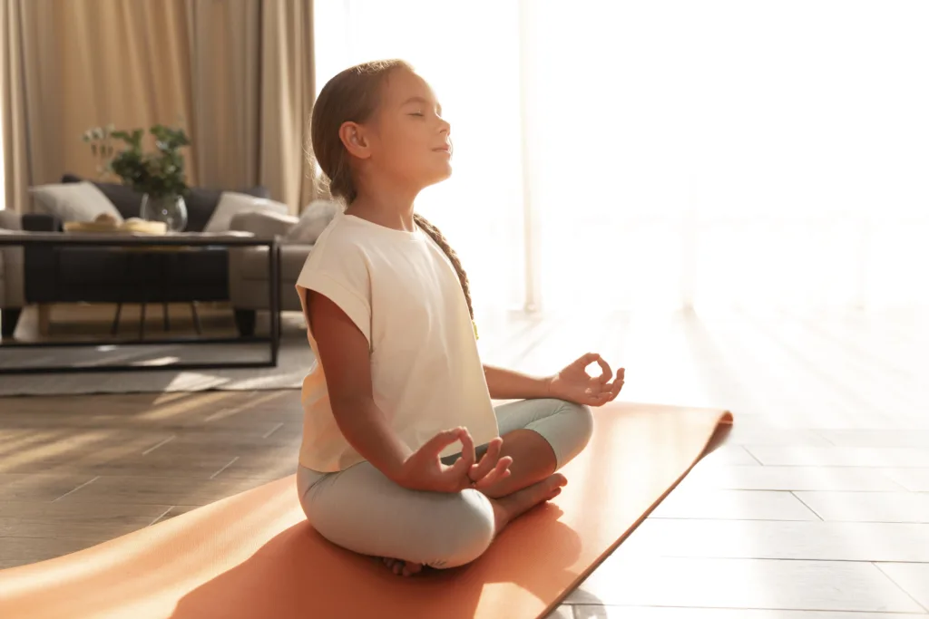 Little girl in yoga pose meditating with eyes closed