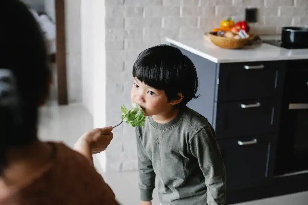 little boy being forced to eat salad