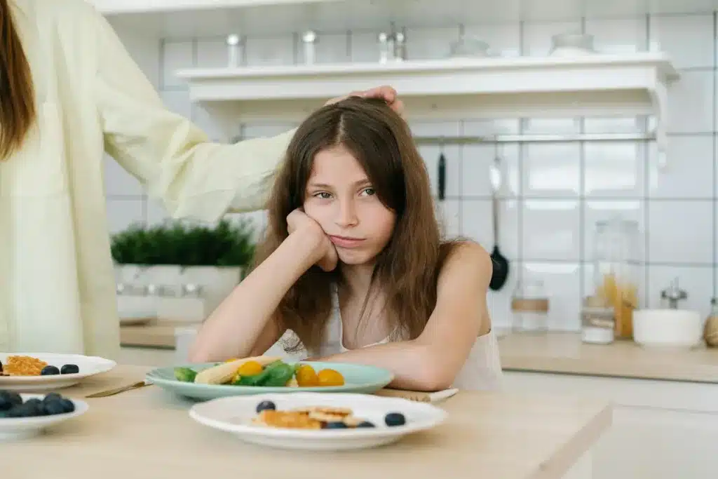 picky eater with a plate with vegetables in front of her
