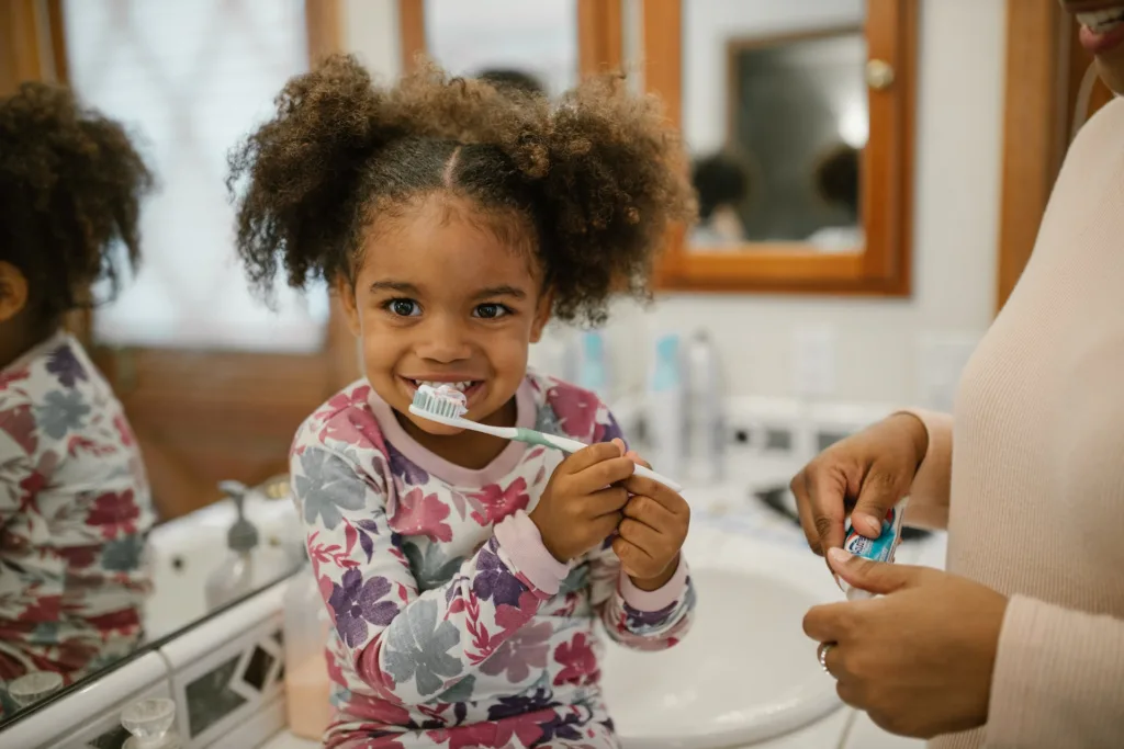 Smiling girl brushes teeth on bathroom sink