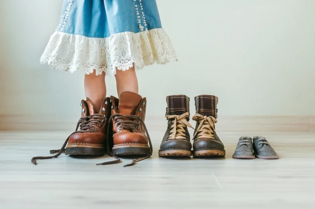 Family shoes line up with daughter trying to fit her father’s shoes