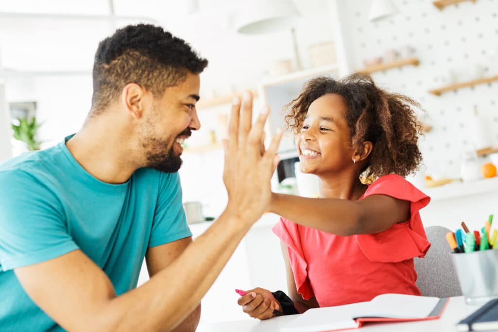 Dad shares a high five with his daughter for a breakthrough in homework