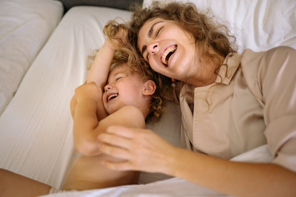 Mom and toddler laughing together at bedtime.