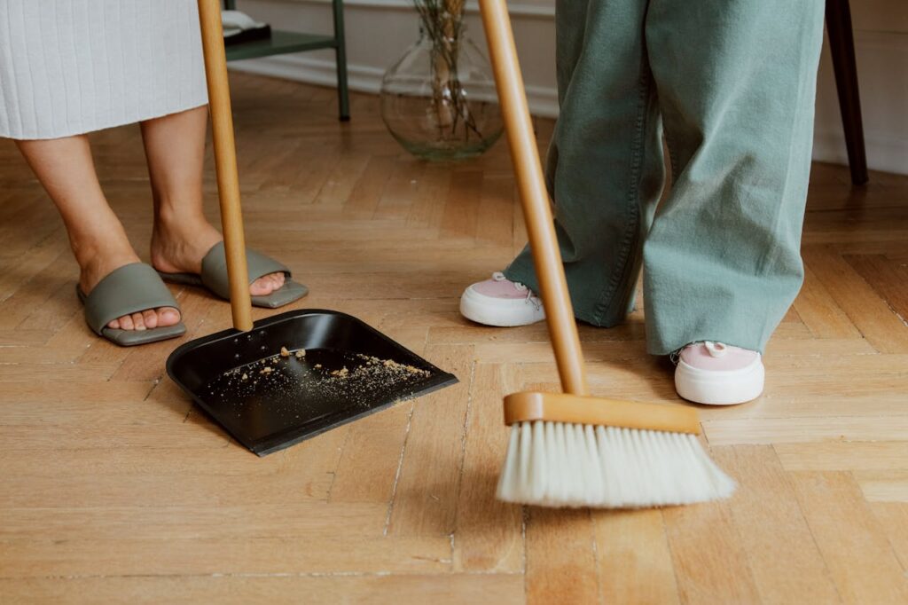 consequence vs punishment: A broom and garbage are on the floor with the legs of a mom and child visible nearby.
