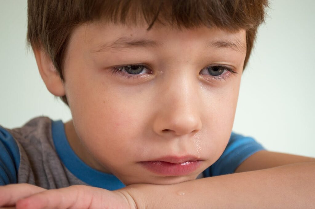 A young boy crying, with tears on his face and a sad expression