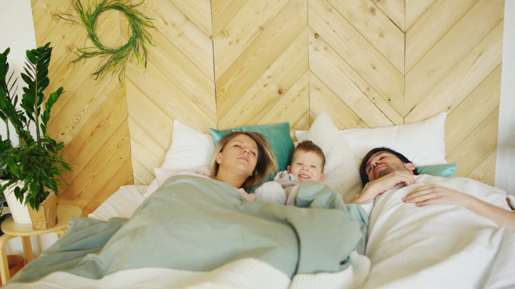 A mother and father lie in bed, their 2-year-old child nestled between them.