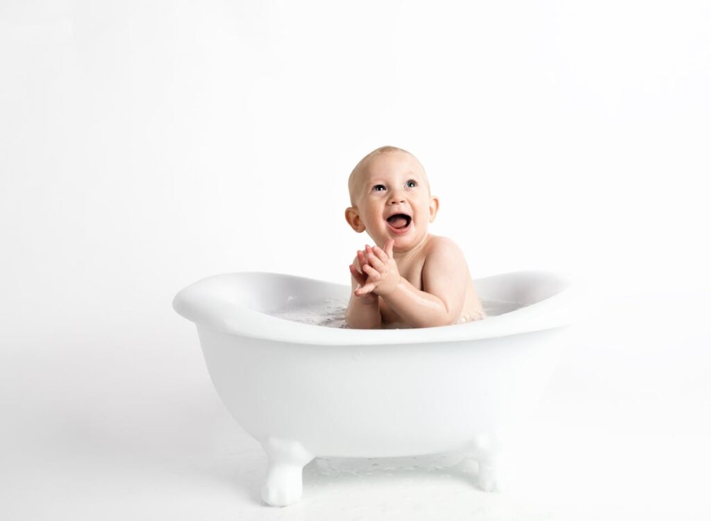 A smiling toddler sitting in a small white bathtub