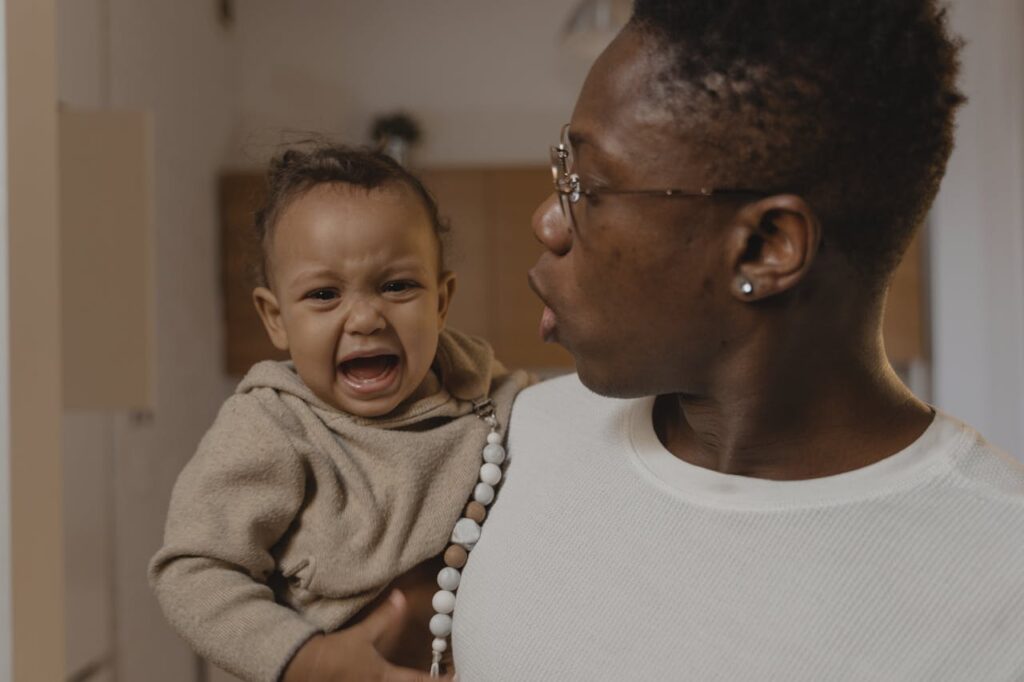 A toddler crying in his mother's arms