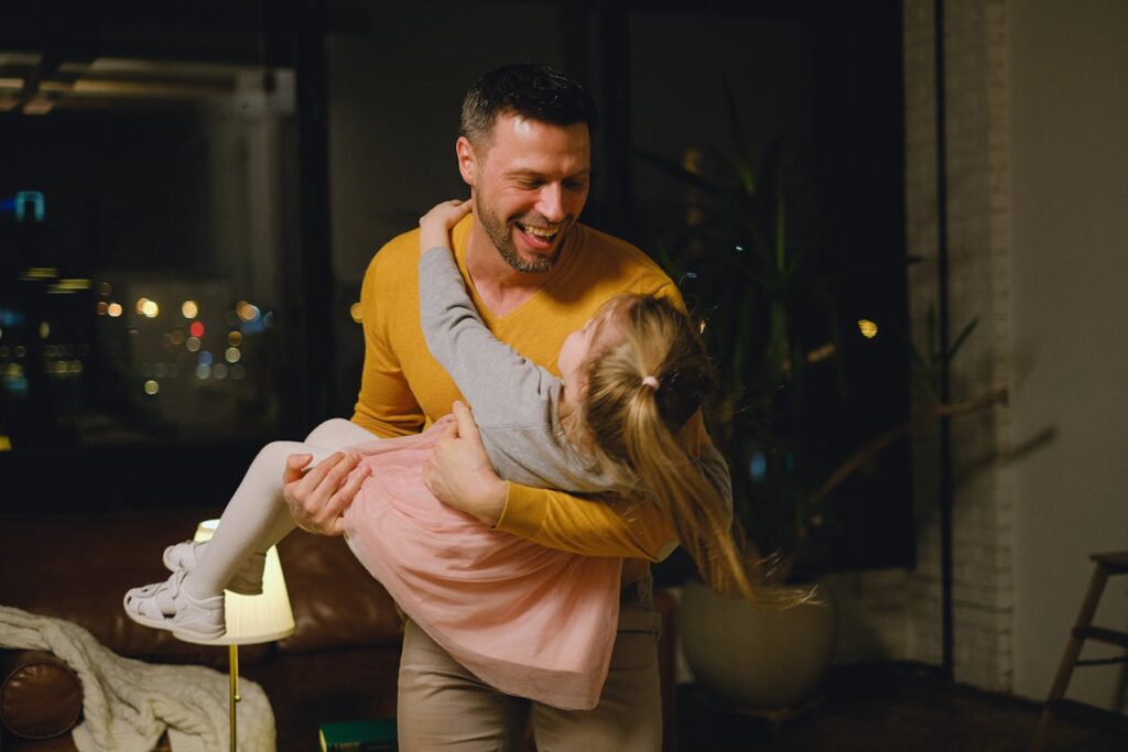 A dad joyfully holds his daughter in his arms while playing together.