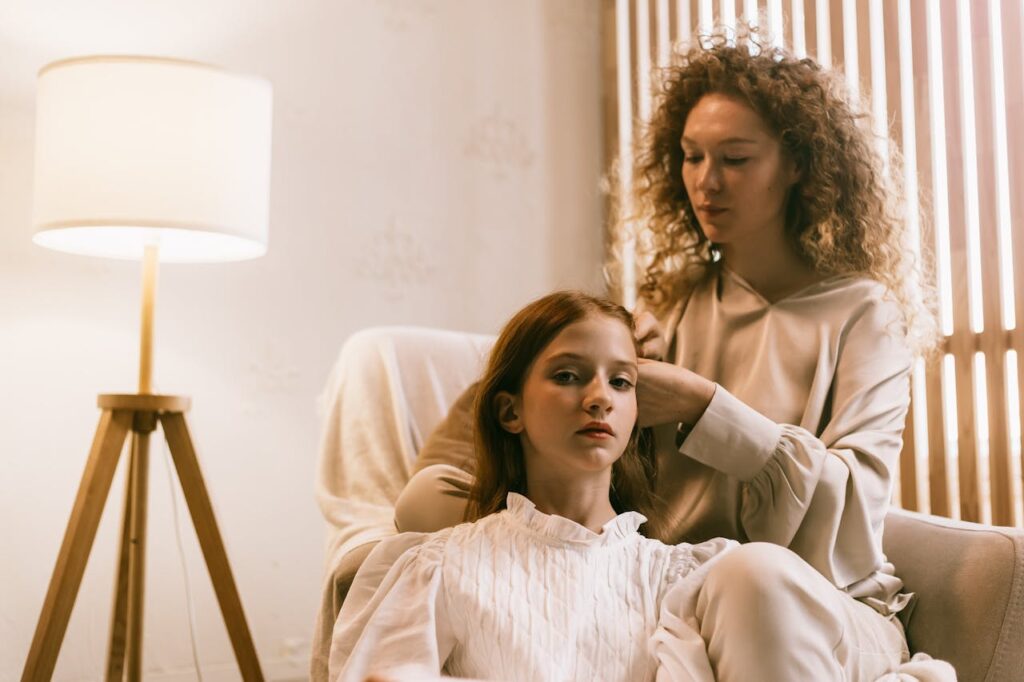 A mom gently braiding her daughter's hair, sharing a quiet bonding moment.